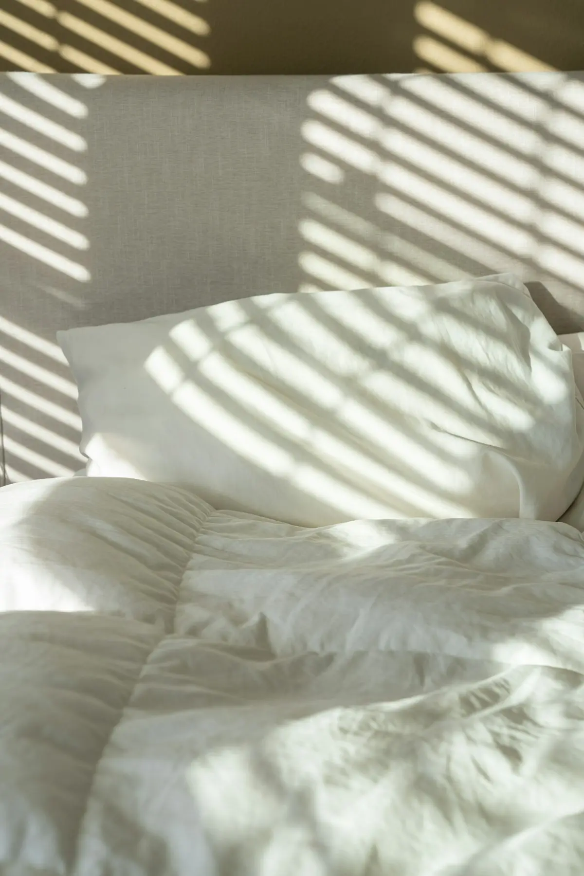 Luz de mañana entrando sobre ropa de cama blanca recién puesta en un apartamento turístico de Madrid